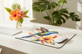 Hummingbird & Hibiscus Mouse Pad displayed on a bright desk with colorful tropical flowers and computer mouse