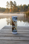 Mallard duck hunting tumbler on a weathered wooden dock at dawn with morning mist over the lake