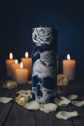 Skull and roses gothic tumbler with white rose petals and candlelight on a dark moody surface